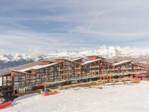 a resort building with snow covered mountains in the background at Appartement spacieux et rénové - Ski aux pieds - Balcon - Wifi - 8/9 pers - FR-1-346-553 in Arc 1800