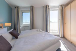 a bedroom with two beds and a large window at Ferienwohnung Ostseesonne mit Balkon - direkt an der Ostsee gelegen in Zingst