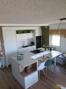 una cocina con encimeras blancas, mesa y sillas en Les Tamaris Vue Mer, en Roscoff