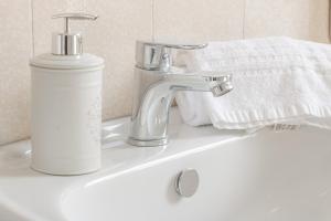 ein Waschbecken mit einem Wasserhahn und einer Flasche Seife in der Unterkunft H11 AI CASTELLETTI Mare - Parcheggio in Arma di Taggia