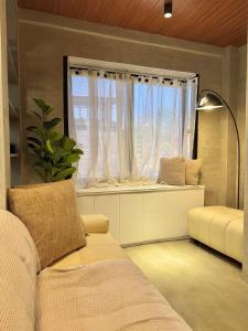 ein Wohnzimmer mit einer Couch und einem Fenster in der Unterkunft K-Ville - Loft House Near Philippine Arena in Sampong