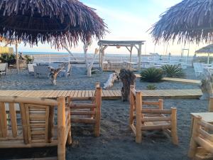a wooden table and chairs on the beach with an umbrella at Lovely house tra pineta e mare in Torre di Montalto