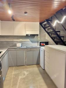 eine Küche mit weißen Schränken und einer Treppe in der Unterkunft K-Ville - Loft House Near Philippine Arena in Sampong