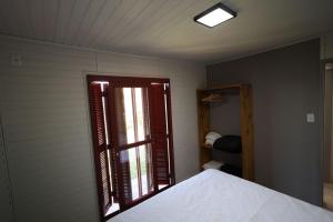 a bedroom with a window and a bed with white sheets at Vila Justina in Monte Belo