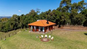 a small house on top of a field with chairs at Vila Justina in Monte Belo