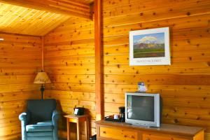 ein Wohnzimmer mit Fernseher und Sessel in der Unterkunft Denali Grizzly Bear Resort in McKinley Park