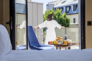 a woman standing on a balcony looking out the window at Radisson Blu Hotel, Rouen Centre in Rouen