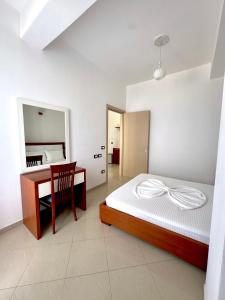 a bedroom with a bed and a desk and a mirror at Blue Paradise Hotel in Orikum