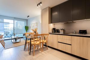 a kitchen with wooden cabinets and a table and chairs at Las Condes Living Arauco Park Gourmet Couple's Pad in Santiago