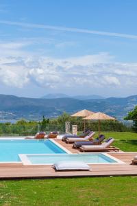 een zwembad met ligstoelen en parasols bij Anemones Villas by Omikron Selections in Spanokhórion