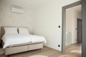 a bedroom with a bed with white sheets and a mirror at Bovi Lux Apartman in Nyíregyháza
