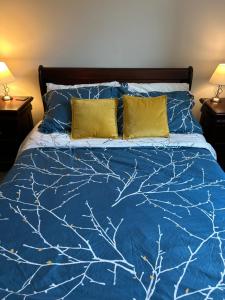a bed with a blue comforter and two yellow pillows at Hebden Rooms in Hebden Bridge