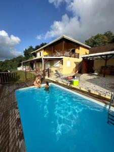 two people in a swimming pool in front of a house at Studio charmant à Rivière-Pilote avec piscine in Rivière-Pilote