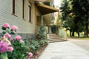 a building with pink flowers next to a sidewalk at Oasi di Famagosta Milano Navigli in Milan