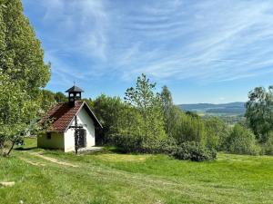 a small building on a grassy hill with a sky at Maringotka a ubytování PodNebesí in Křemže