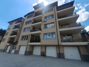 a tall apartment building with four white garage doors at Apartment Aria 6 in Velingrad