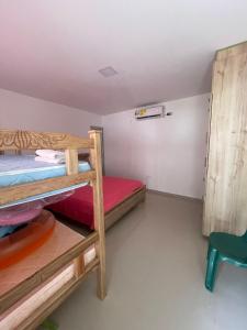Habitación con 2 literas y una silla verde. en Villa Isabel Casa Patio, en Ríohacha