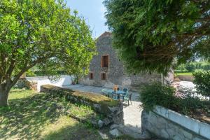 a stone house with a table and a tree at Casa La venta de Pedro in Ribadesella