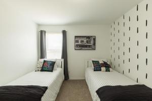 two beds in a room with white walls at Valley Forest 65in TV Games Lackland Pet in San Antonio