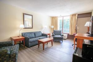 una sala de estar con sofá y sillas en una habitación de hotel en OYO hotel Greensboro east I 40, en Greensboro