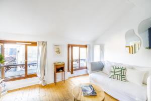 ein Wohnzimmer mit einer weißen Couch und einem Tisch in der Unterkunft Proche Château Appartement Calme & Familiale in Versailles