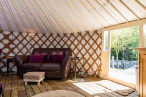 a living room with a leather couch in a yurt at Yurt with Hot Tub near Hartington, Peak District in Buxton