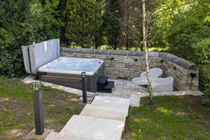 a hot tub sitting in a yard next to a stone wall at Yurt with Hot Tub near Hartington, Peak District in Buxton