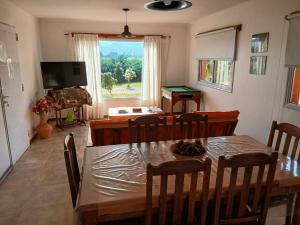 a dining room with a table and a television at Cabañas Rincon de Campo San Andres De Las Sierras in Villa Ventana