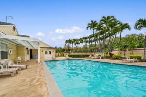 a swimming pool with chairs and palm trees at Big Island Fairway Terrace A-202 by Coldwell Banker Island Vacations in Waikoloa Village