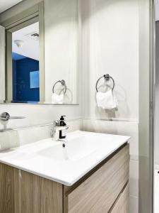 un bagno bianco con lavandino e specchio di Canal Luxe Burj 1BR Sleeps 4 with Pool and Gym a Dubai