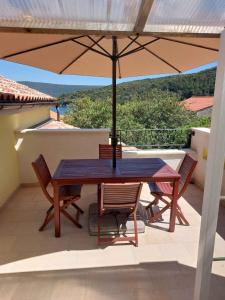 House Valun 42 في فالون: طاولة وكراسي مع مظلة على شرفة