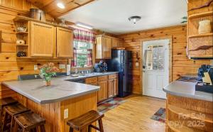 a kitchen with wooden cabinets and a black refrigerator at Fox Creek Cabin 3: Creekside Cabin in the Smoky Mountains! in Bryson City +4 photos