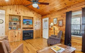 a living room with a ceiling fan and a fireplace at Fox Creek Cabin 3: Creekside Cabin in the Smoky Mountains! in Bryson City
