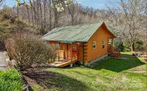 a cabin in the woods with a green roof at Fox Creek Cabin 3: Creekside Cabin in the Smoky Mountains! in Bryson City