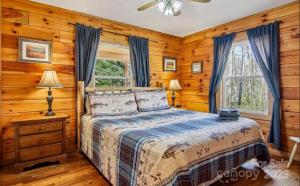 a bedroom with a bed in a room with wooden walls at Fox Creek Cabin 3: Creekside Cabin in the Smoky Mountains! in Bryson City