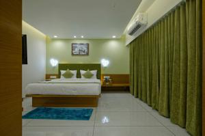 SarkhejHOTEL AURELLIA的一间卧室配有床和绿帘