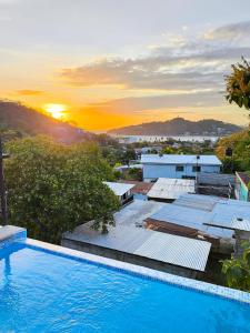a swimming pool with the sunset in the background at Buena Onda Backpackers in San Juan del Sur