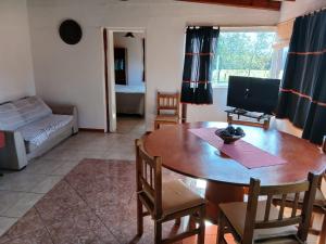 Una sala de estar con una mesa de madera y un televisor. en Cabañas Rincon de Campo San Andres De Las Sierras, en Villa Ventana