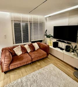 a brown leather couch in a living room with a flat screen tv at Unique House for Football Fans-Wroclaw Final- near Stadium in Wrocław