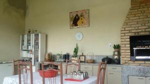 a kitchen with a table and chairs and a clock on the wall at Sítio Rodrigues in Pedro Leopoldo