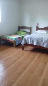 two beds sitting in a room with wooden floors at Sítio Rodrigues in Pedro Leopoldo +9 photos