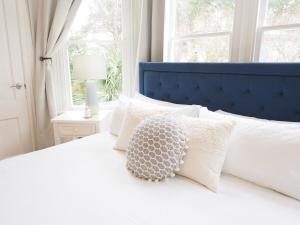 a white bed with a blue headboard and pillows at Stunning Forsyth Park Victorian - Walk to it all! in Savannah