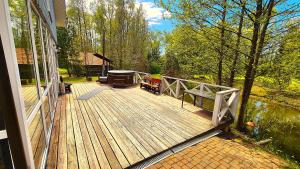 a wooden deck on a house next to the water at Atostogų namas su baseinu, jacuzzi ir pirtimi in Klaipėda