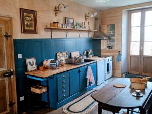 eine Küche mit blauen Schränken und einem Tisch darin in der Unterkunft Charmante maison de village à Ménil-sur-Saulx - FR-1-585-172 in Ménil-sur-Saulx