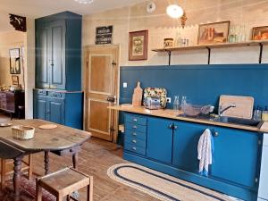 eine Küche mit blauen Schränken, einem Tisch und einem Waschbecken in der Unterkunft Charmante maison de village à Ménil-sur-Saulx - FR-1-585-172 in Ménil-sur-Saulx + 9 Fotos