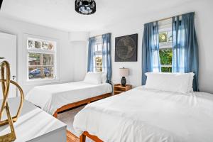 two beds in a room with two windows at Poolside Getaway, Close To Dt Coastal Beach in West Palm Beach