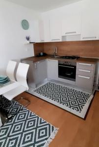 a kitchen with white cabinets and a sink and a rug at Apartman Lopar 2,Crikvenica in Crikvenica
