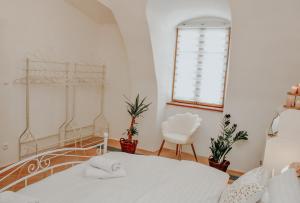 ein Schlafzimmer mit einem weißen Bett und einem Stuhl in der Unterkunft Apartmán Baumgartner in Banská Štiavnica