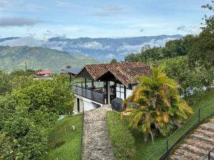 a house with a balcony with a view of the mountains at Acaima Café Lodge in Sasaima