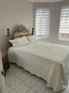 een slaapkamer met een bed met witte lakens en 2 ramen bij Seacastle Beach Penthouse in Montego Bay